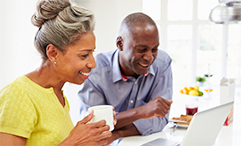 older couple in kitchen sitting around computer