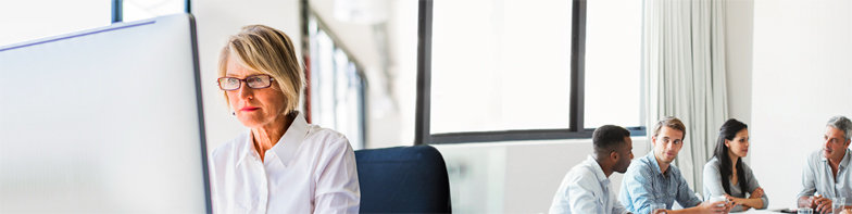 woman with glasses in office sitting at computer