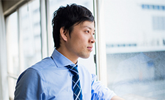 man in office with tie looking out window