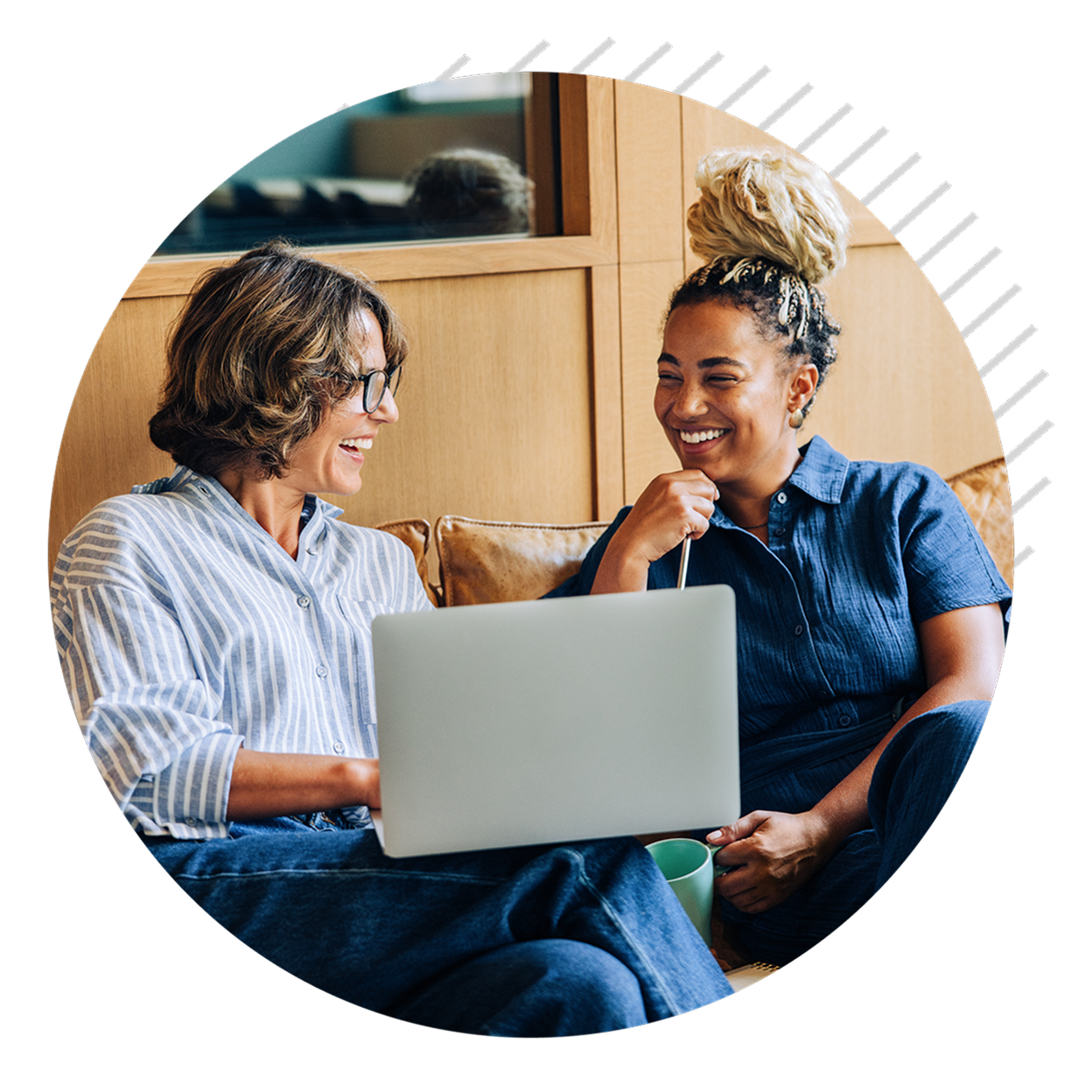 Two women sit in front of laptop, speaking and smiling.