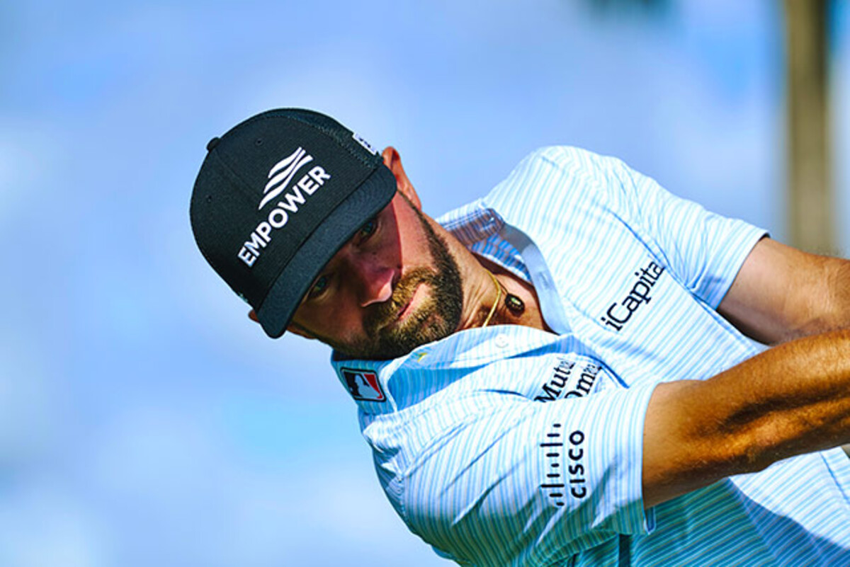 Golfer Cam Young swinging golf club wearing Empower hat