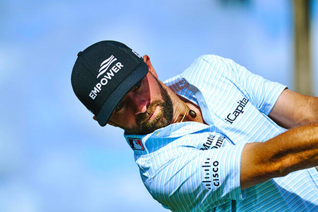 Golfer Cam Young swinging golf club wearing Empower hat