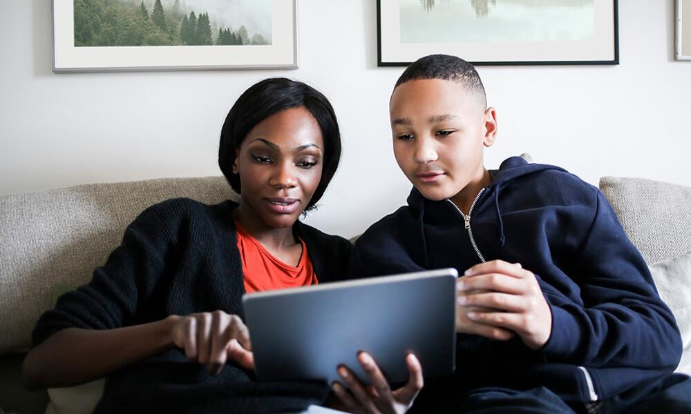 a mother and son view a tablet device reviewing financial information