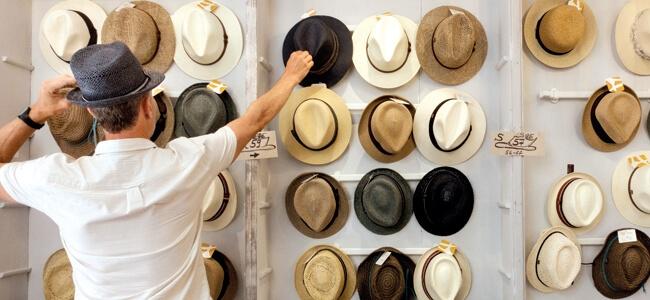 A man trying on hats at a store