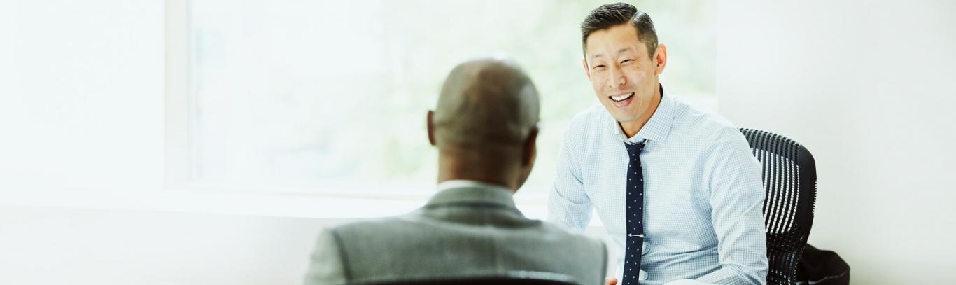 A financial advisor sits with client, smiling and talking