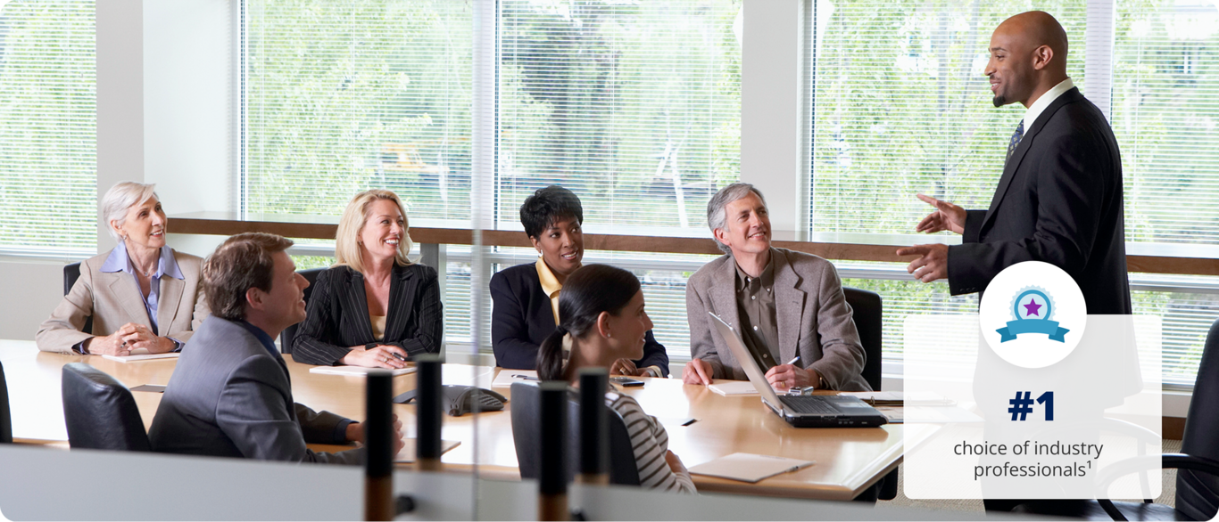 A man stands speaking to a conference room of employees. #1 choice of industry professionals.