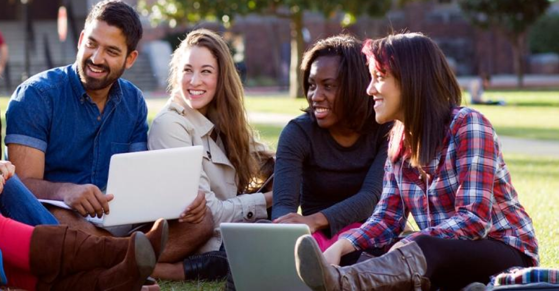 Group of students sitting on a college lawn chatting in a circle