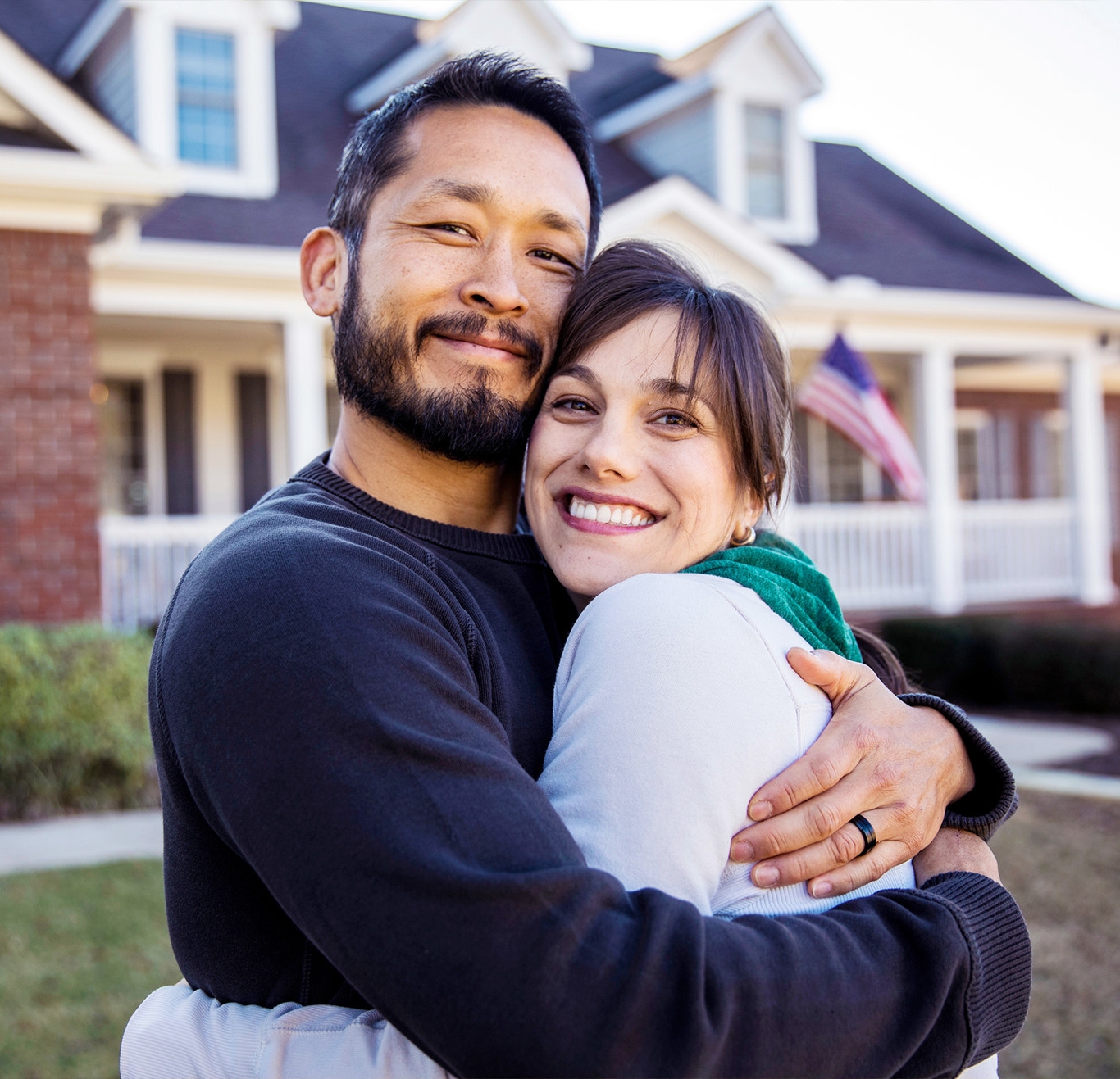 Man and Woman hugging in front of a house
