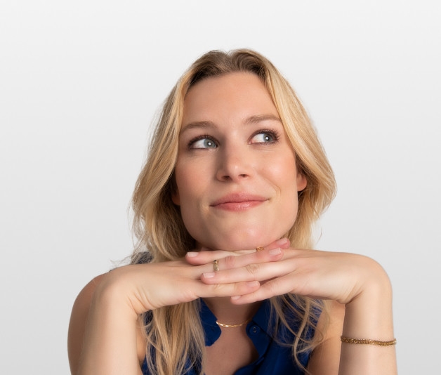 A blonde woman sits with her hands crossed 