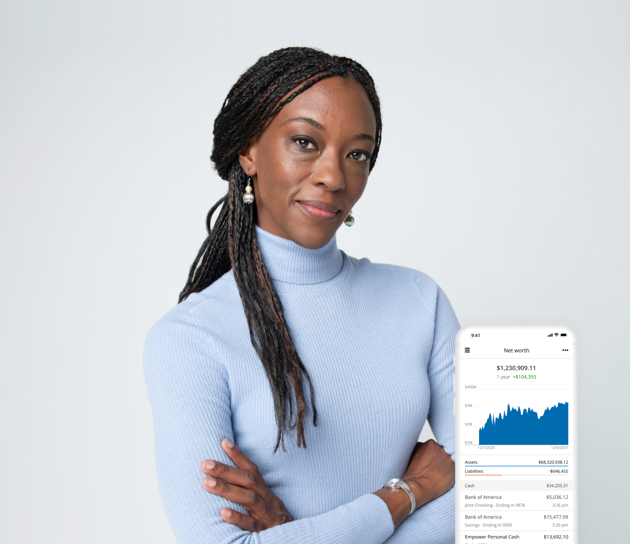 woman with blue turtleneck sweater crossing arms smiling, phone screenshot of financial chart bottom right of image 