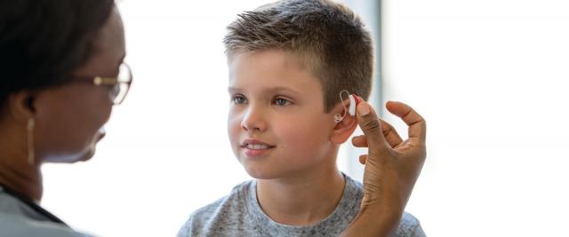 A child at a doctors office receiving a hearing aid