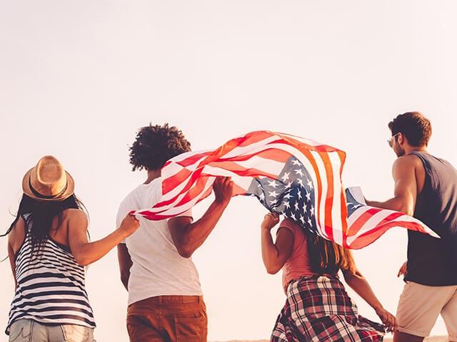 Four individuals holding an American flag