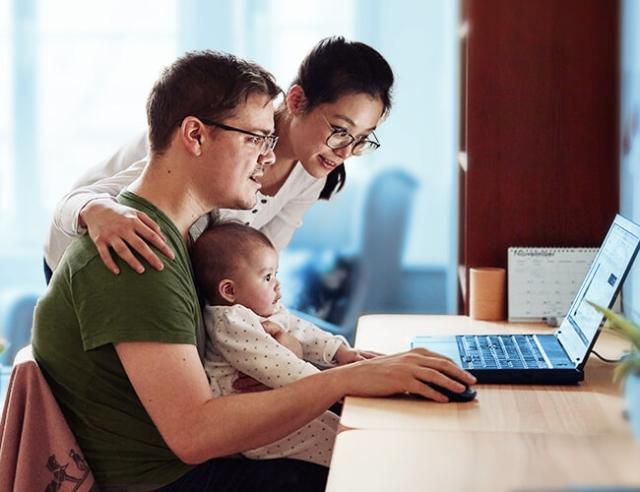 A husband, wife and baby work on financial plans on laptop computer.