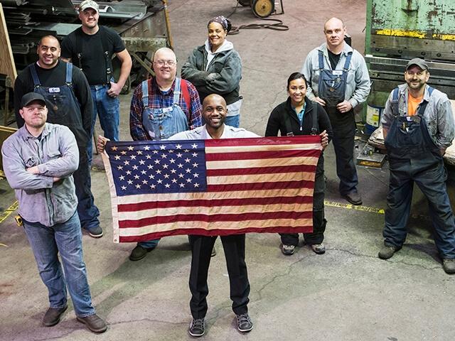 Diverse workers stand together holding American flag