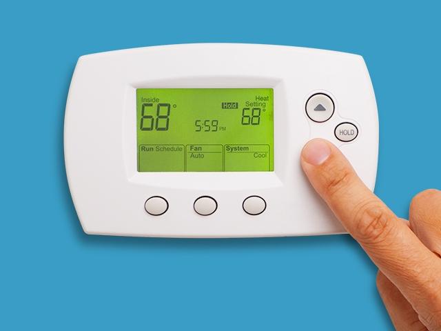 A finger adjusts the temperature on thermostat
