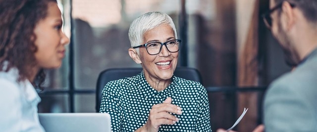 woman sitting at desk, smiling, discussing financial investments