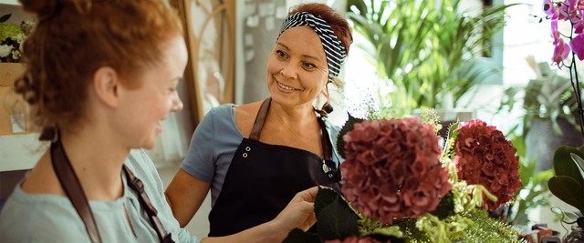 Two women in a flower shop converse about bouquet of flowers