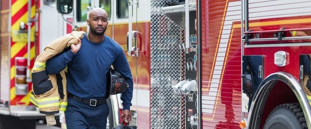 A fireman carries gear from fire truck