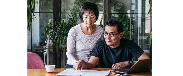 husband and wife sitting at desk reviewing financial documents