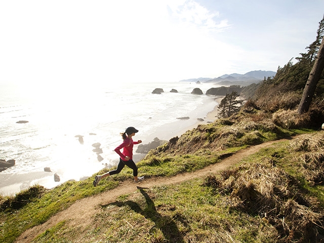 A woman jogs along a trail near a coast line