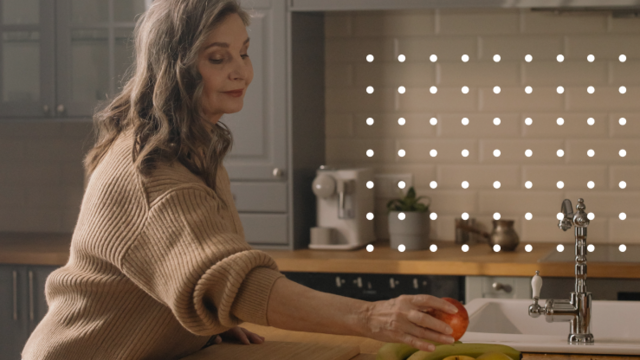 Silver-haired women sets fruit on kitchen counter