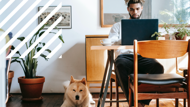 man sits at desk with dog at feet
