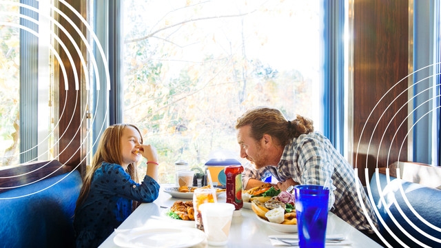 parent and child eat at restaurant