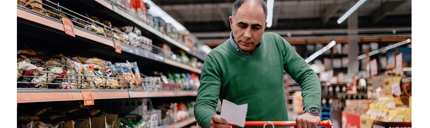 A man shops from a list at grocery store